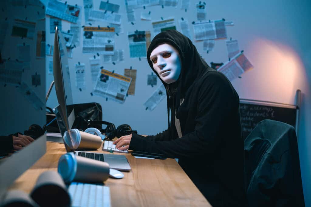 What a cyber attack means - Jon Cosson CISO - hacker in mask developing malware at his workplace