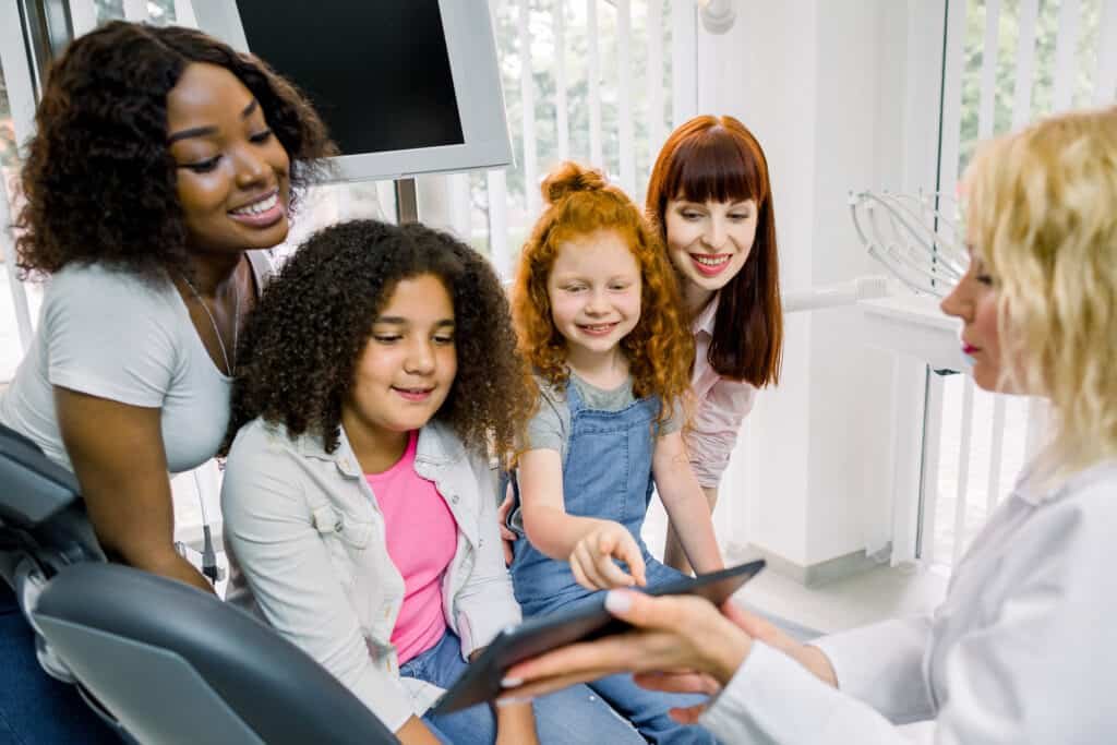 A family looking at a tablet with a health proffesional