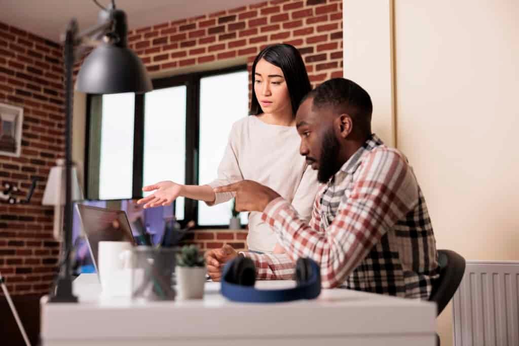 A couple viewing a laptop on a desk discussing how to keep childen safe online