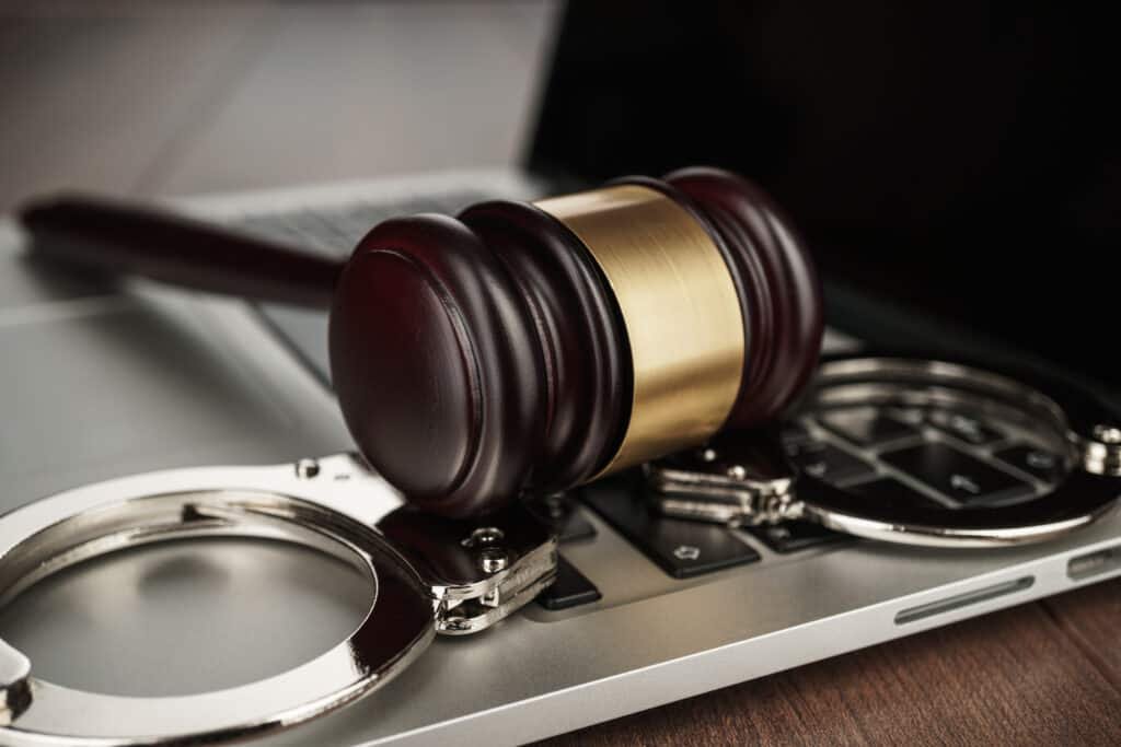 A Laptop with Handcuffs and a judges hammer resting on top