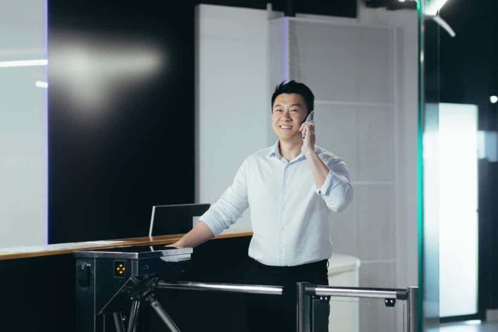 A young businessman passes through the security desk and pass in the morning to the office and business center for work. Talking on the phone, in a hurry, smiling