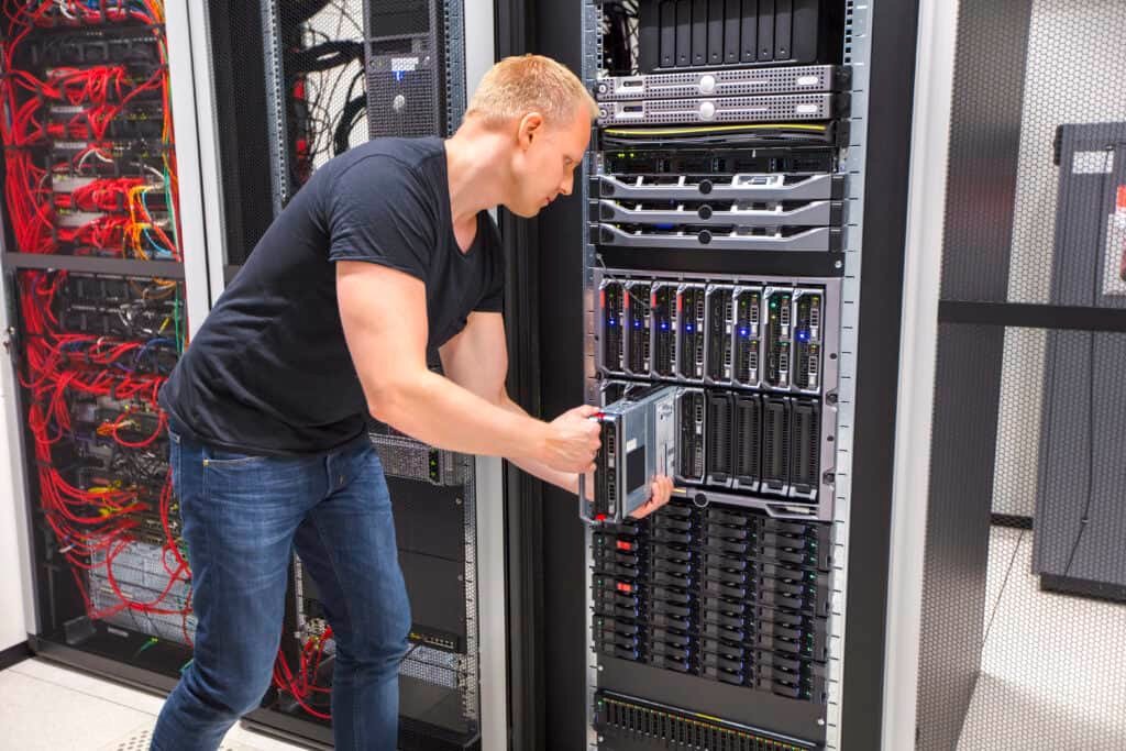 An adult male computer engineer installing blade server in chassis within a datacenter