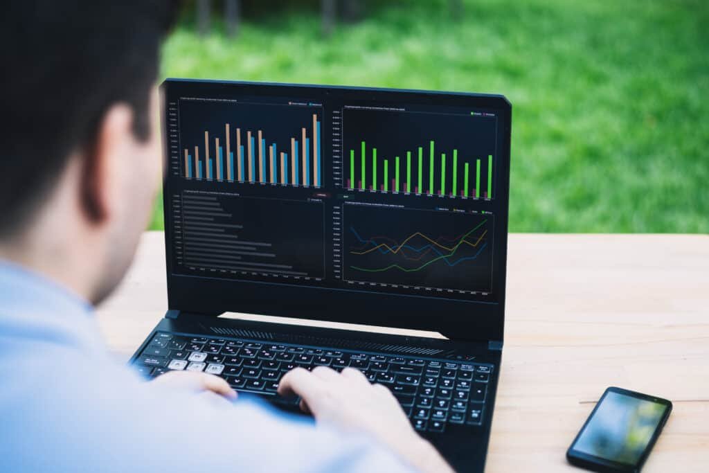 Immediate Connect Scam or trading platform. Man using a trading application on a laptop on a bench in a garden