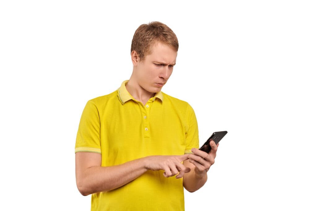 Confused young guy with smart phone tapping touchscreen isolated on white background.