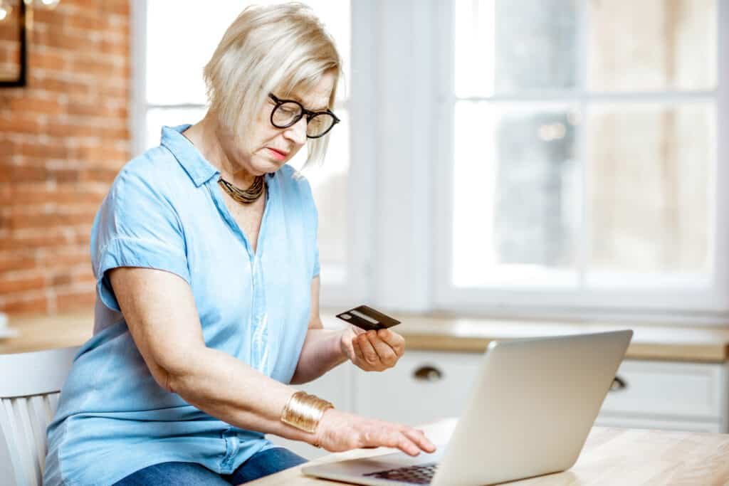 Senior woman shopping online using credit card and laptop at home