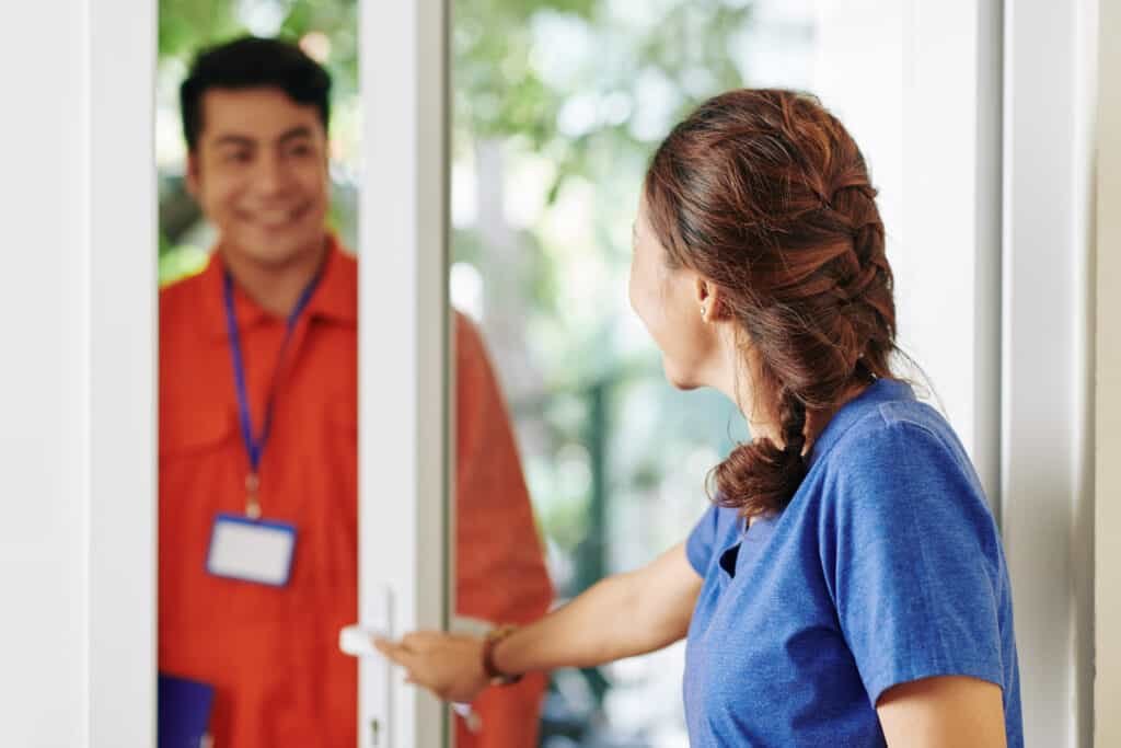 Woman opening entrance door to let in a delivery driver