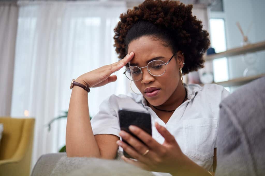 Woman, stress and reading her smart phone at home for notification of a social media scams
