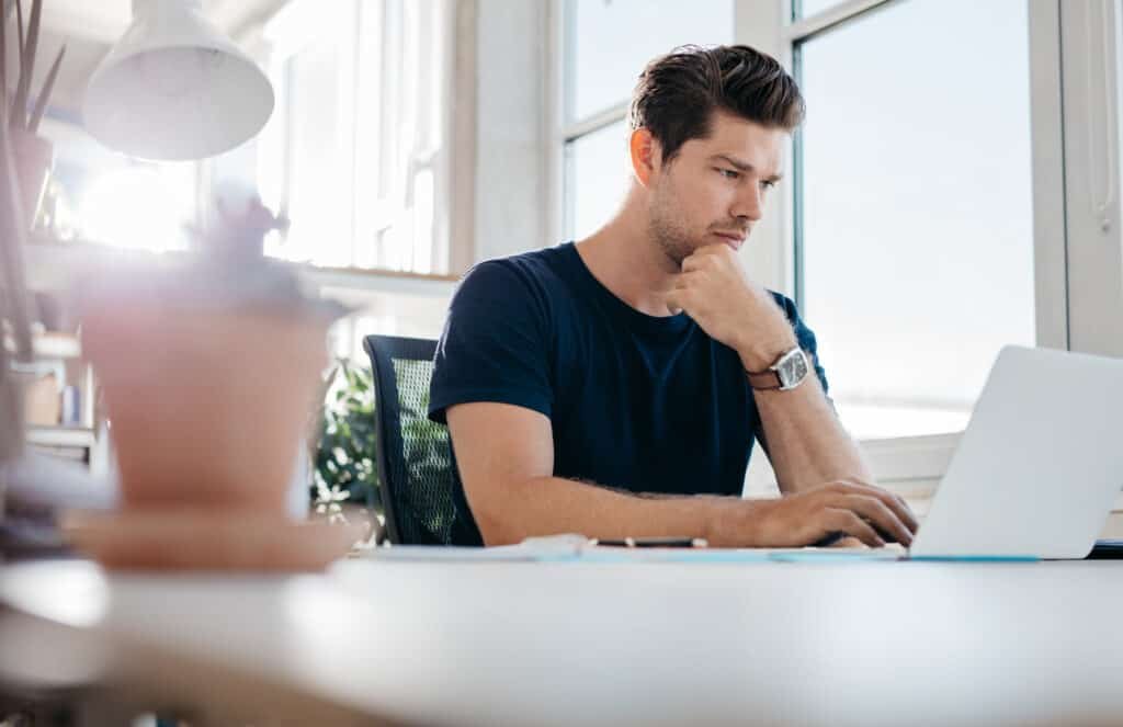 Young man using laptop, browsing Vinted chating via Vinted online chat