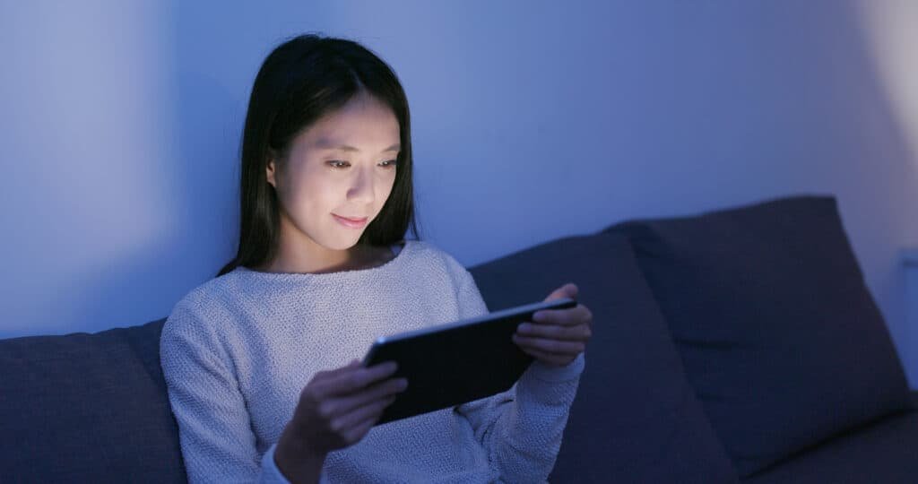 Woman using a tablet computer at night using the Vinted online chat feature