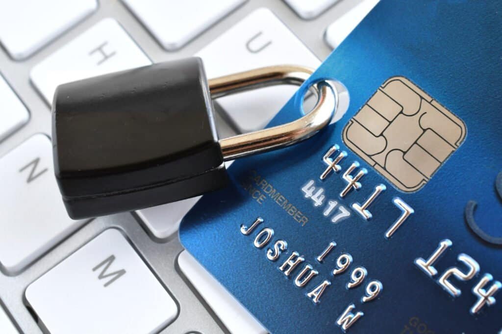 A credit card with a padlock forced through it on a white keyboard, denoting that you should stay safe online