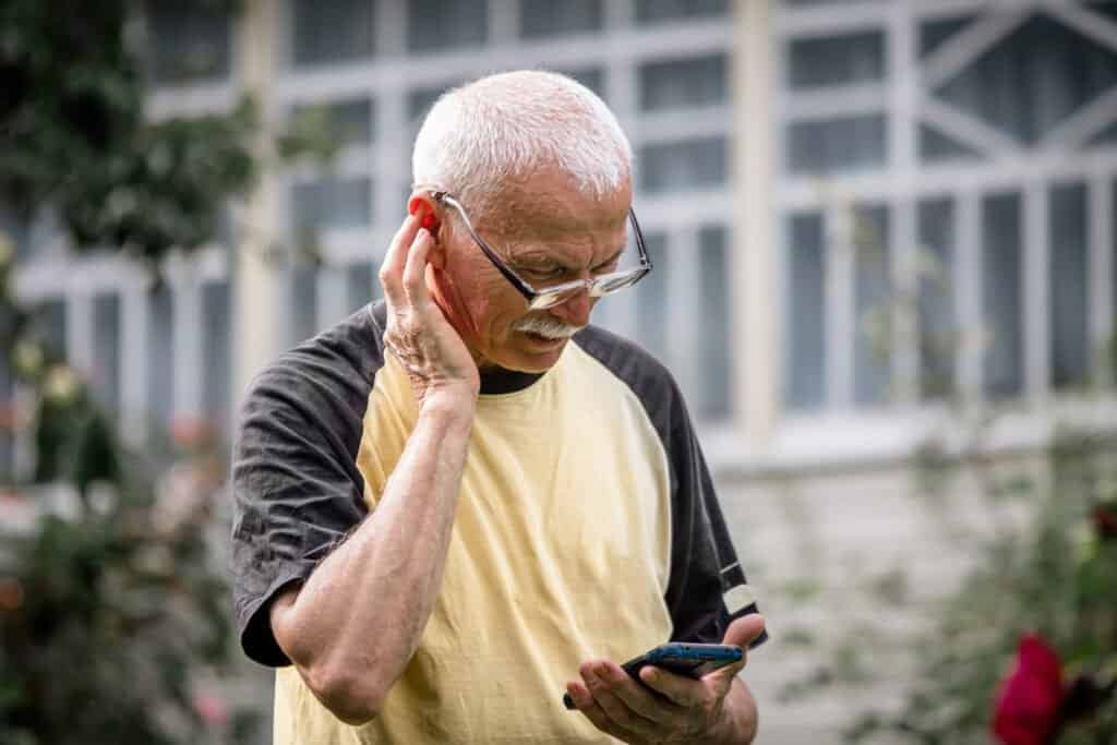 An older man recieving regular calls using phone scams and looking concerned.