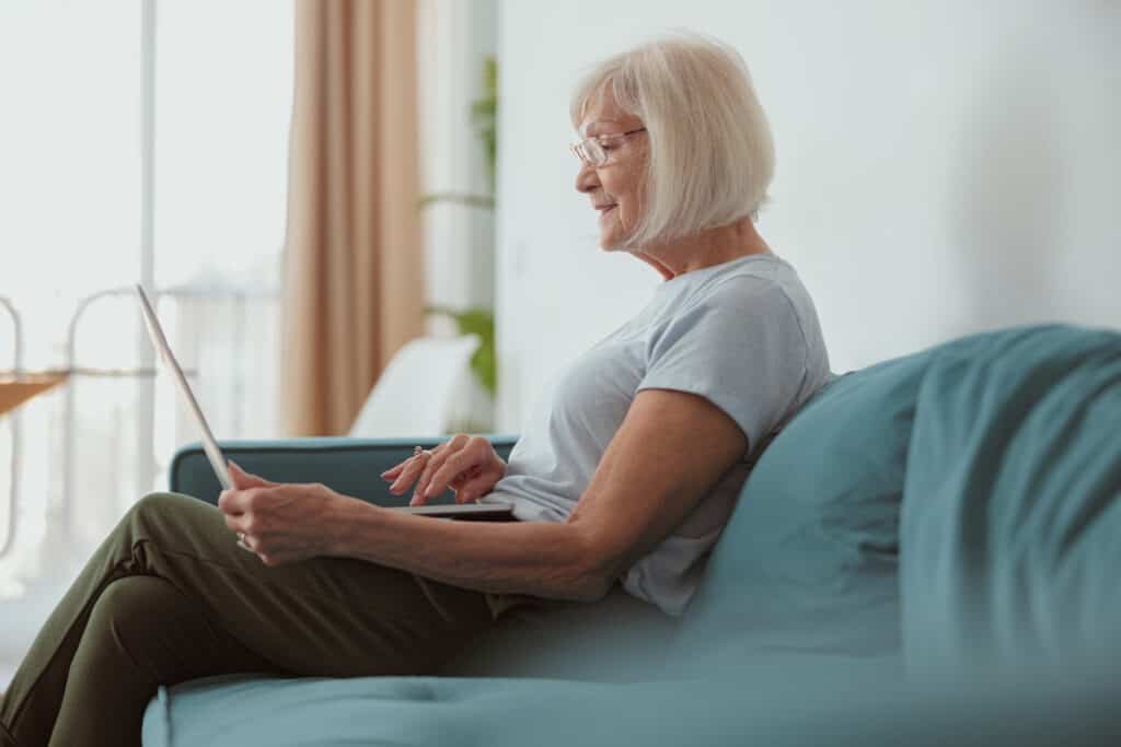 A senior woman sitting on modern sofa and browsing laptop computer attempting to protect her primary email address
