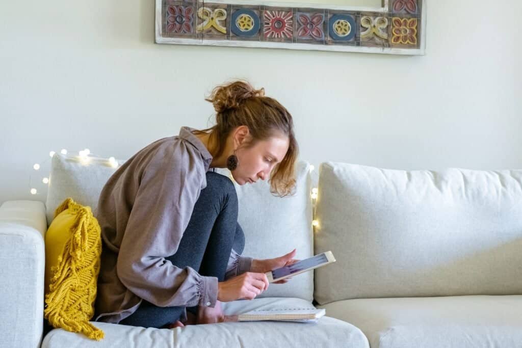 A young woman on a white sofa online shoping on Facebook Marketplace via her tablet