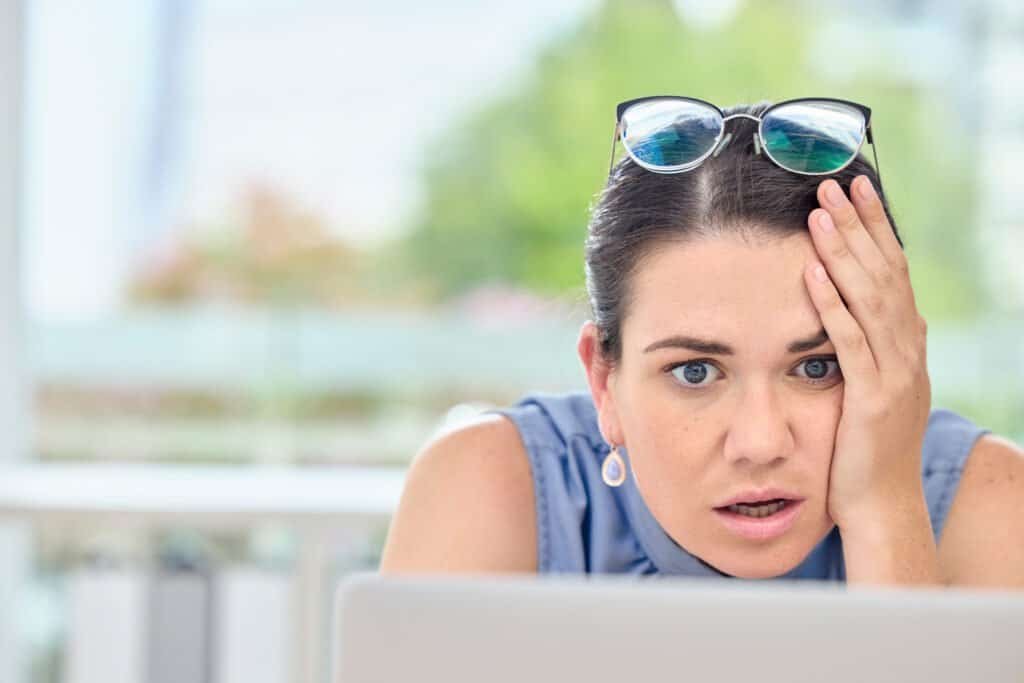 Shocked and stressed woman on computer as she clicked on a phishing email from Amazon scammers