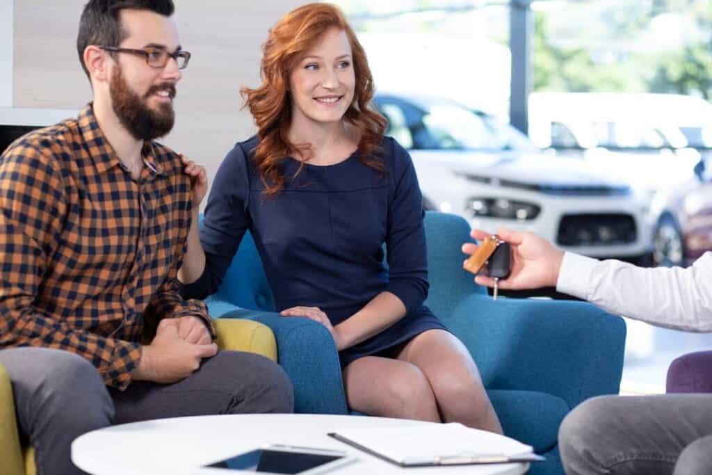Smiling and happy couple buying a new car in exclusive showroom