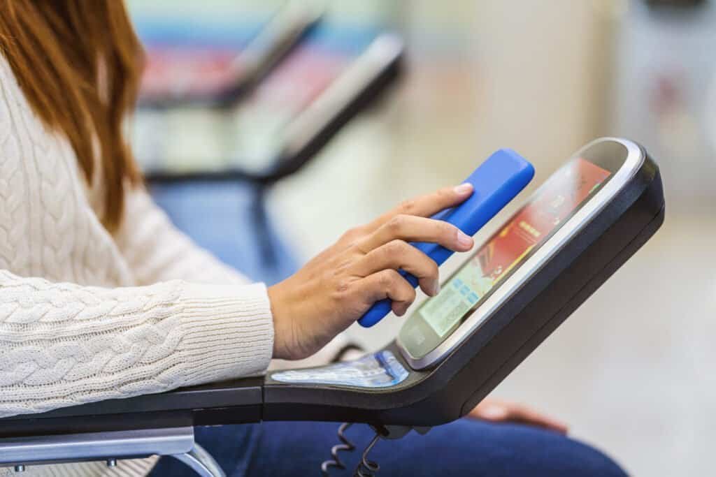 Closeup passenger hand holding and scanning mobile phone with qr code scanner machine of message chair in airport. This is an example of QR Code Scams.