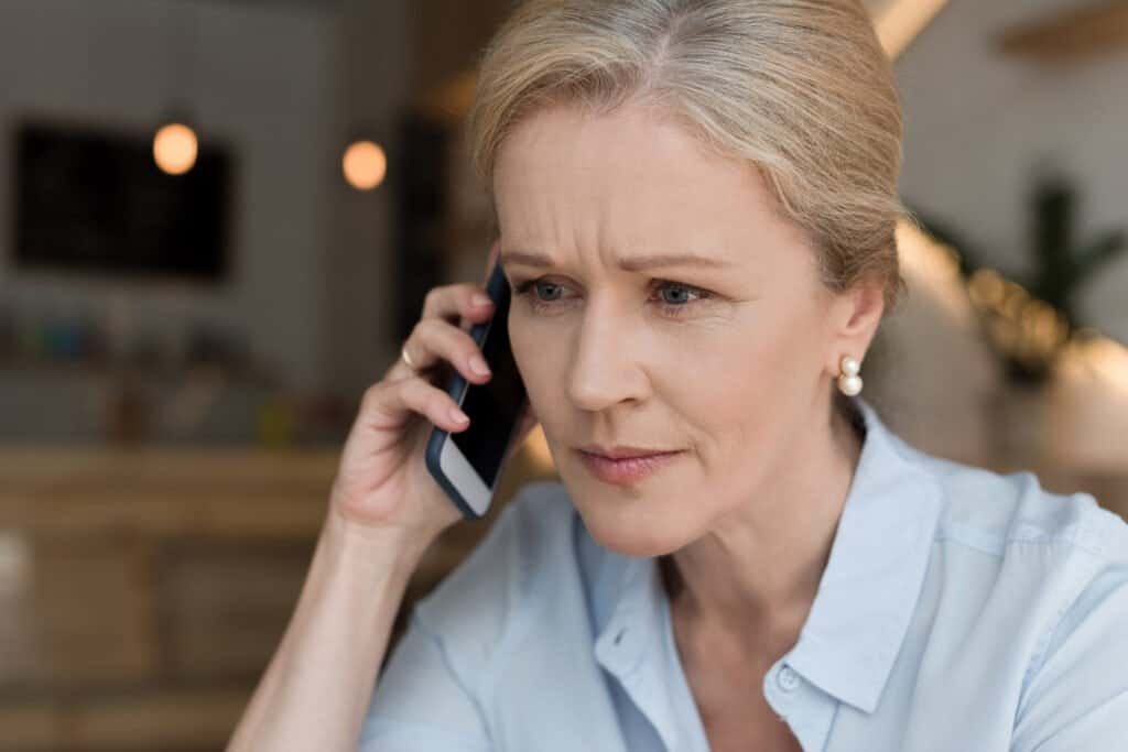 close-up portrait of a mature woman talking on smartphone to her bank to report an EE Scam