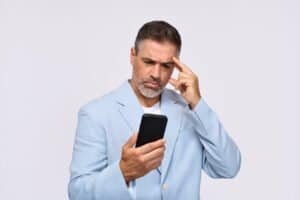 Click on the image of the concerned middle aged man checking his smart phone to connect to the blogpost - Tax Refund Scams