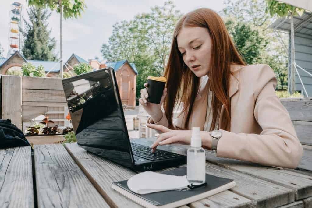 A woman using a laptop whilst drinking a coffee