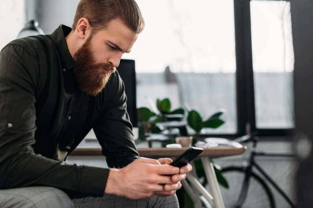 A young man sitting and looking at smartphone after his facebook account hacked email and phone changed