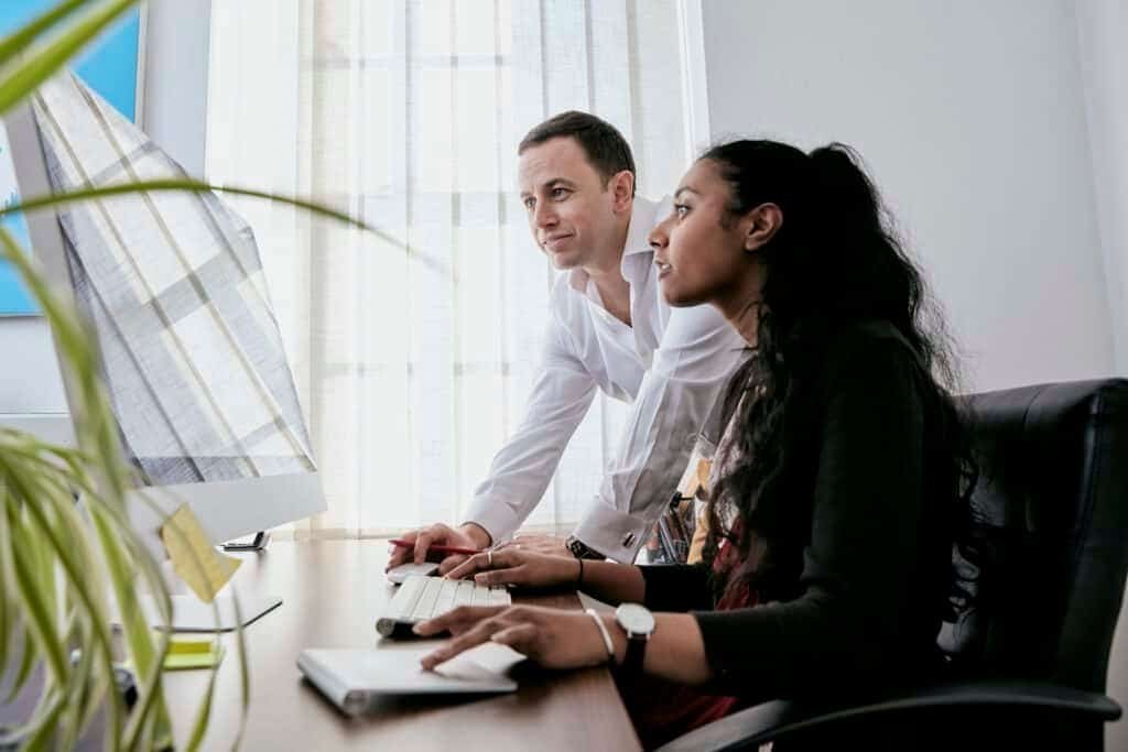 A woman using a computer with a man watching her demonstrate