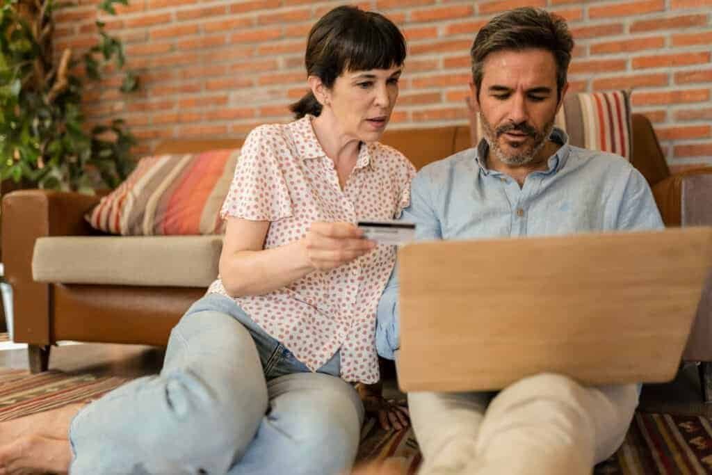 Man and Woman on a latop, using a credit card, potentially being scammed