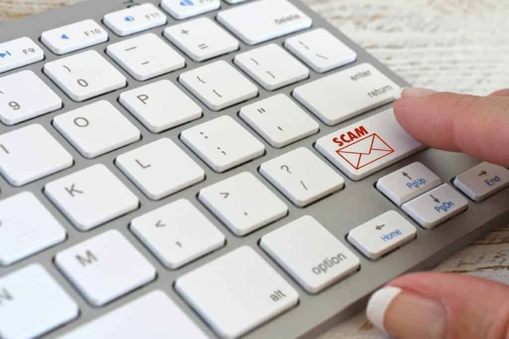 Close up of a keyboard with white keys and one button has a Scam written on it with an image of an email in red - Depitcing be wary of Fedex scam emails.