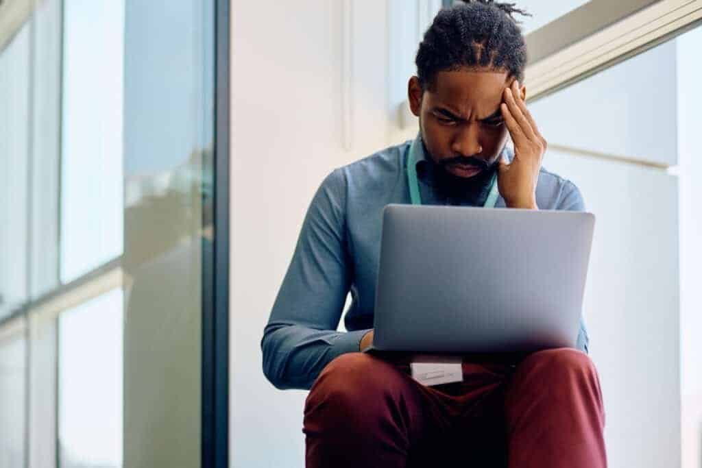 Distraught man recieving a fake Vinted email whilst on laptop